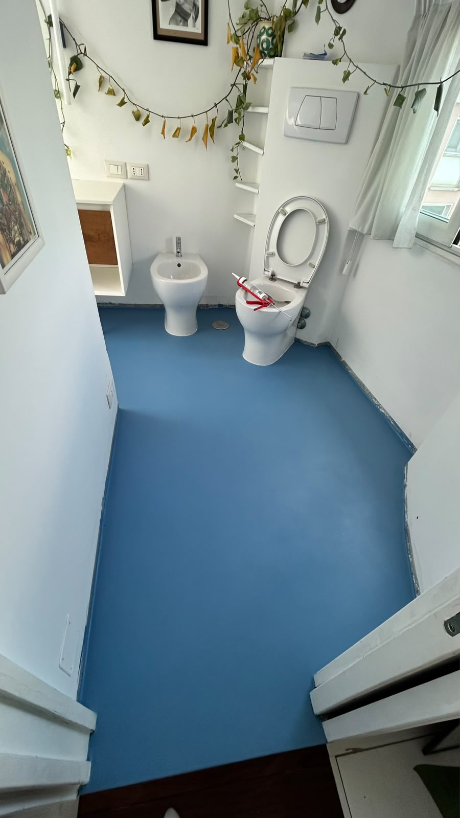 Prima mano di finitura colorata del pavimento in resina nel bagno di Monteverde